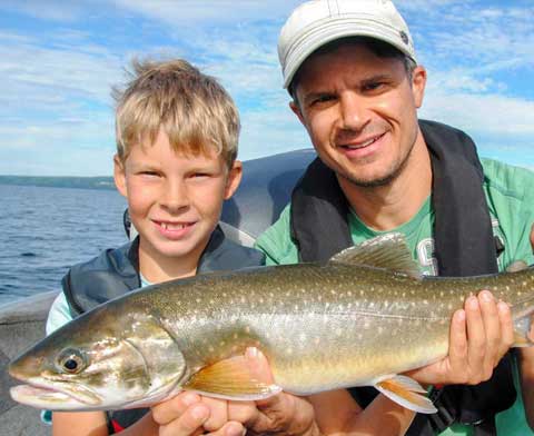 Vater und Sohn sitzen in einem Boot und halten einen großen Fisch vor sich