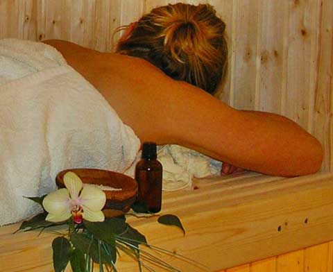 Eine Frau liegt entspannt auf einer Holzbank und wartet auf ihre Massage